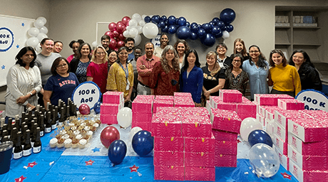 The Human Genome Sequencing Center team poses behind a large spread of treats and drinks, with balloons set all around the room.