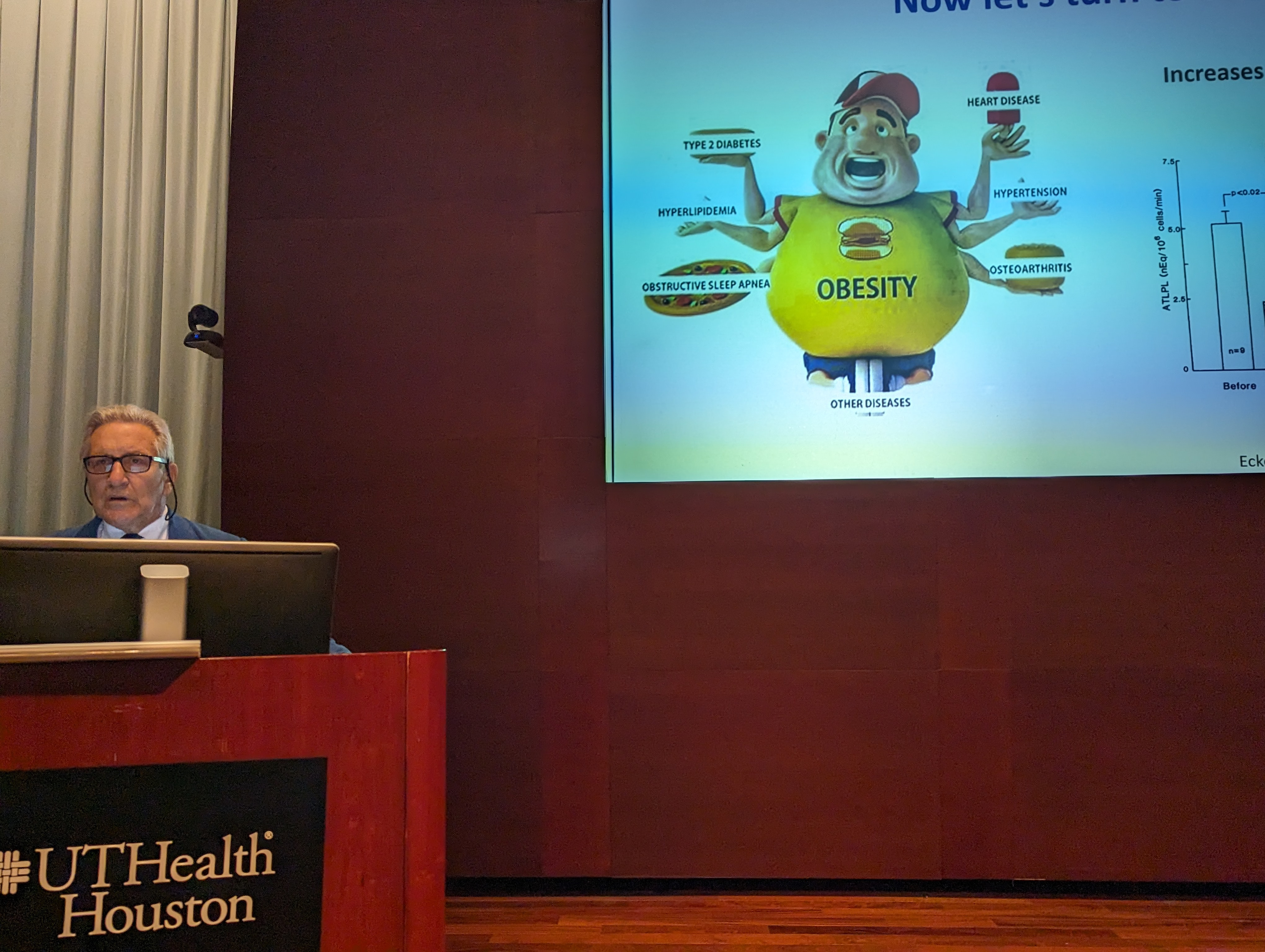 man speaking in front of a screen with a slide on it