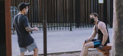 Two people exercising outdoors while wearing face masks.