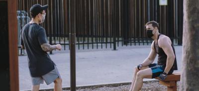 Two people exercising outdoors while wearing face masks.