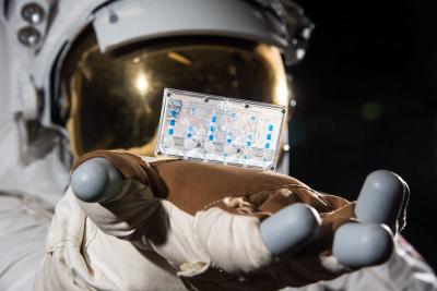 A space suit holds a tissue chip.