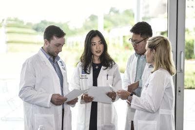 Four young medical students compare notes by a window