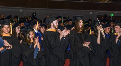 A photo of graduates clapping during their commencement ceremony. 