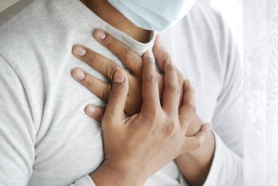 Photo of a man clutching his chest to indicate he is having trouble breathing.