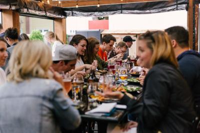 A group of friends enjoy a meal out together in a crowded restaurant.