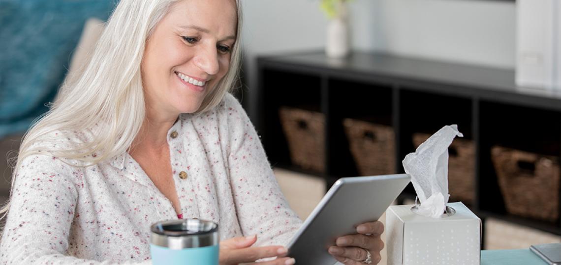 A person at home reading information on a tablet computer