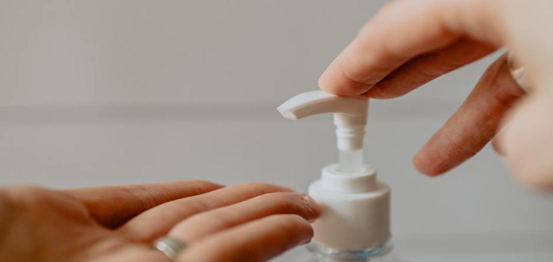 A person getting soap from a pump bottle to wash their hands.