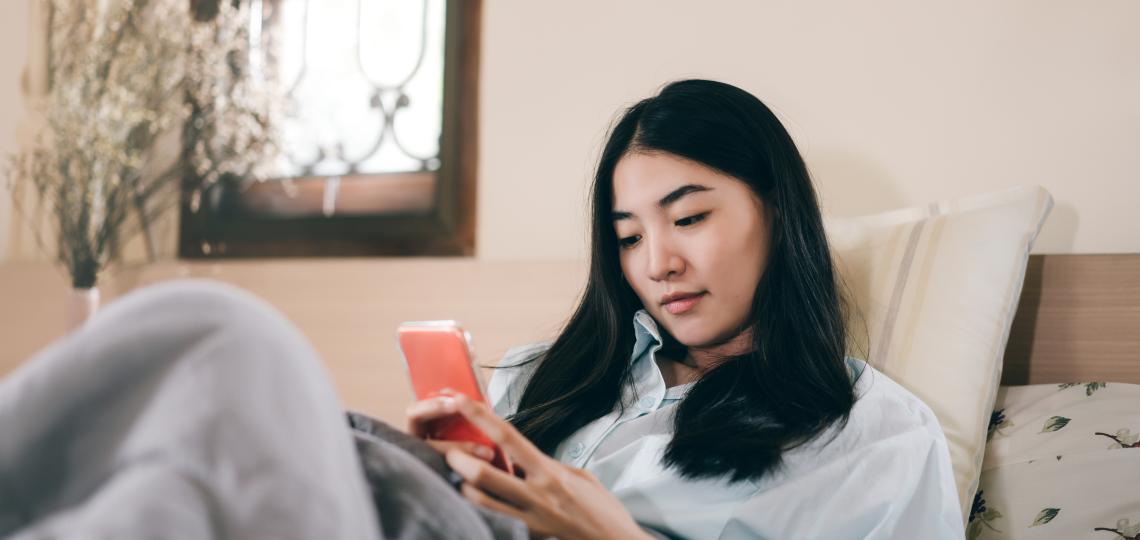 Woman in bed looking at her phone