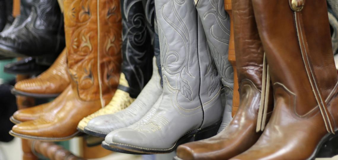 Photograph of brown and grey cowboy boots lined up on display shelf.