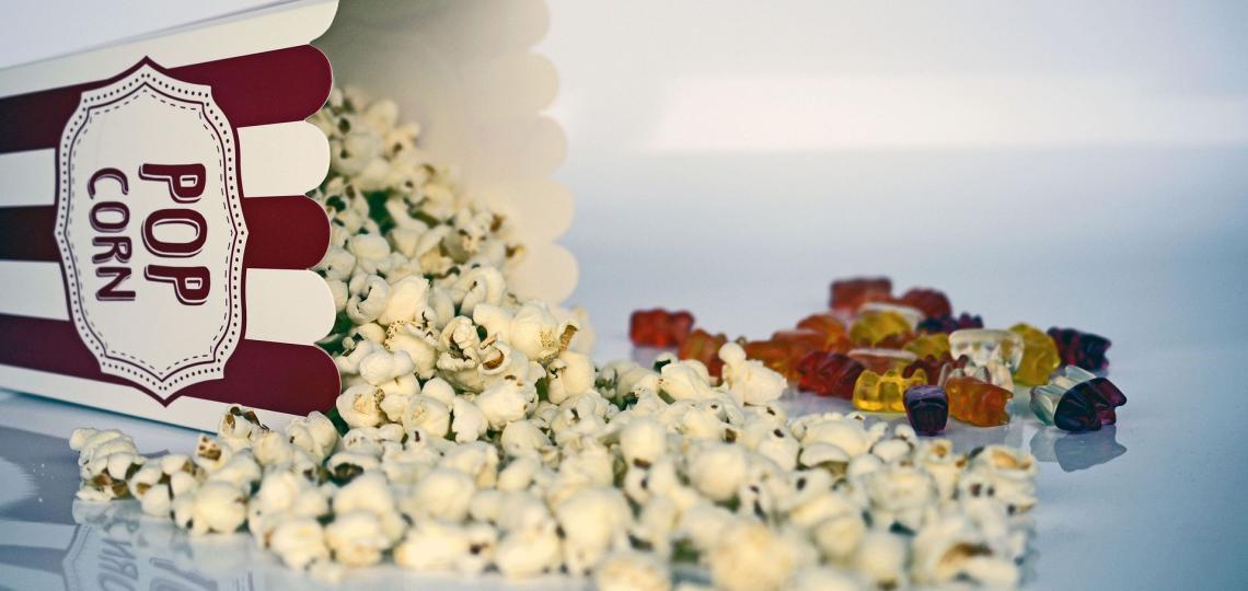 Photo of popcorn and gummie bears to represent movie snacks.