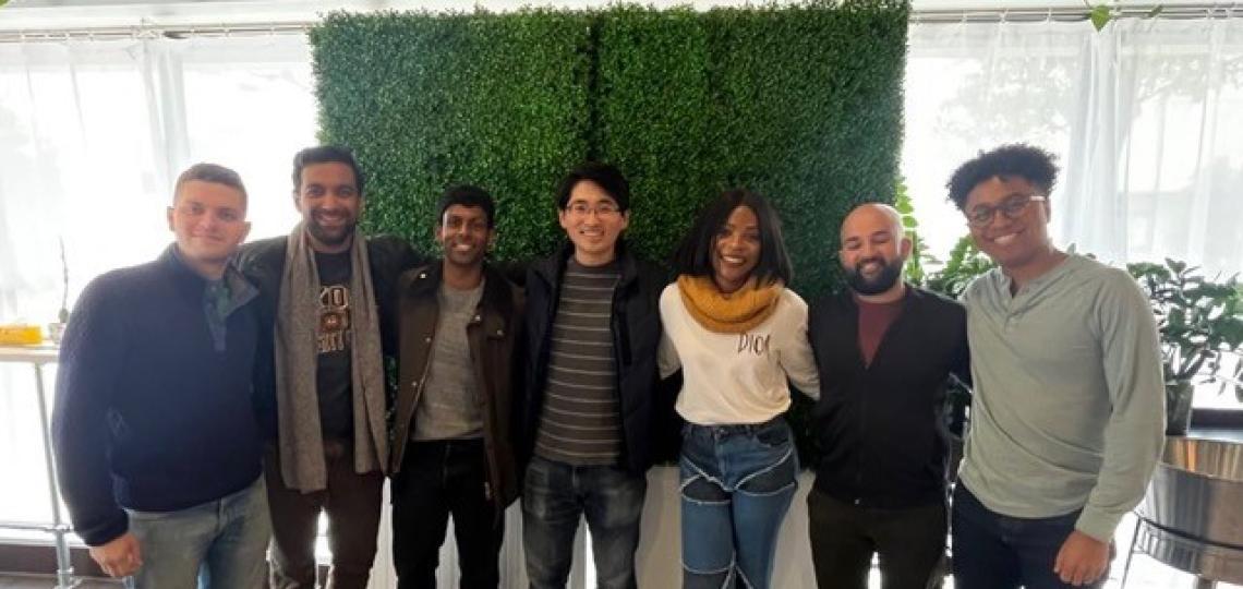 GI Professional Development members pose together in front of a grass wall