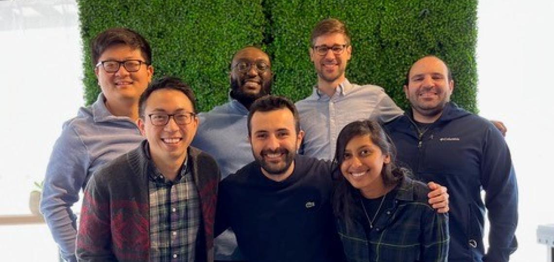 GI Professional Development members pose together in front of a grass wall