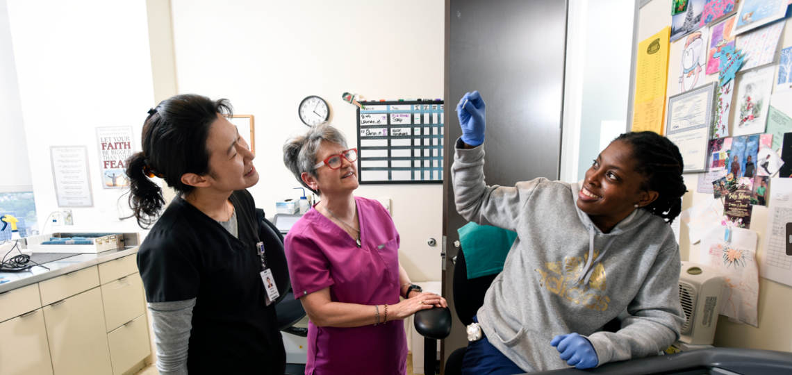 A dermatology fellow shows research materials to mentors
