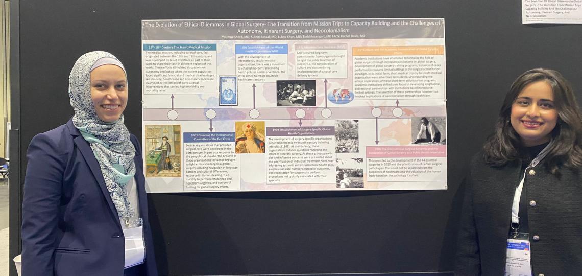 Two residents stand in front of a poster presentation