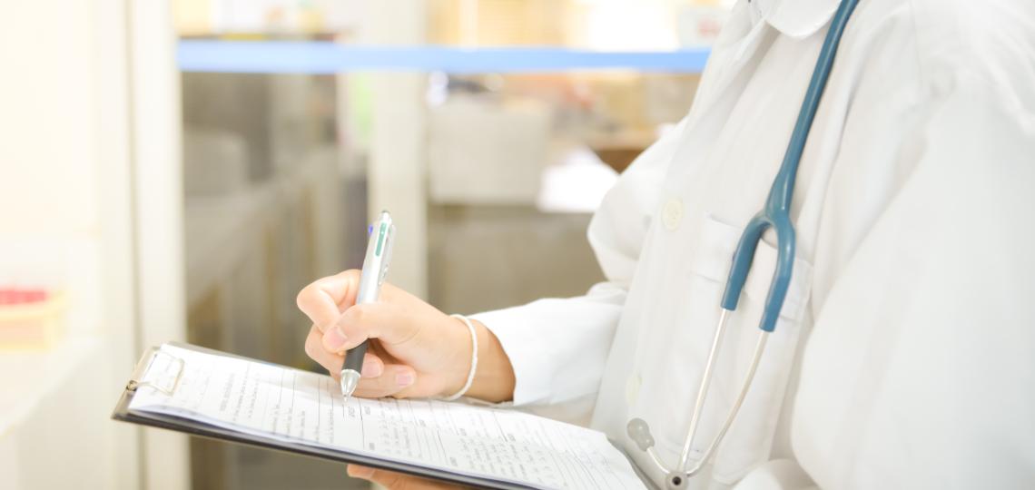 Photo of doctor writing on pad