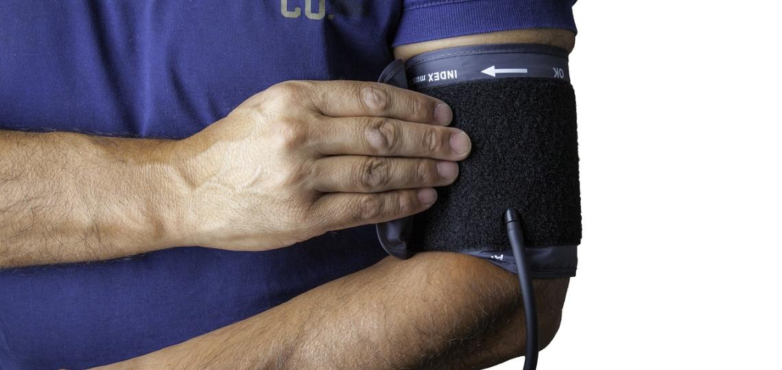 Photo of a man's arm wearing a blood pressure cuff. 