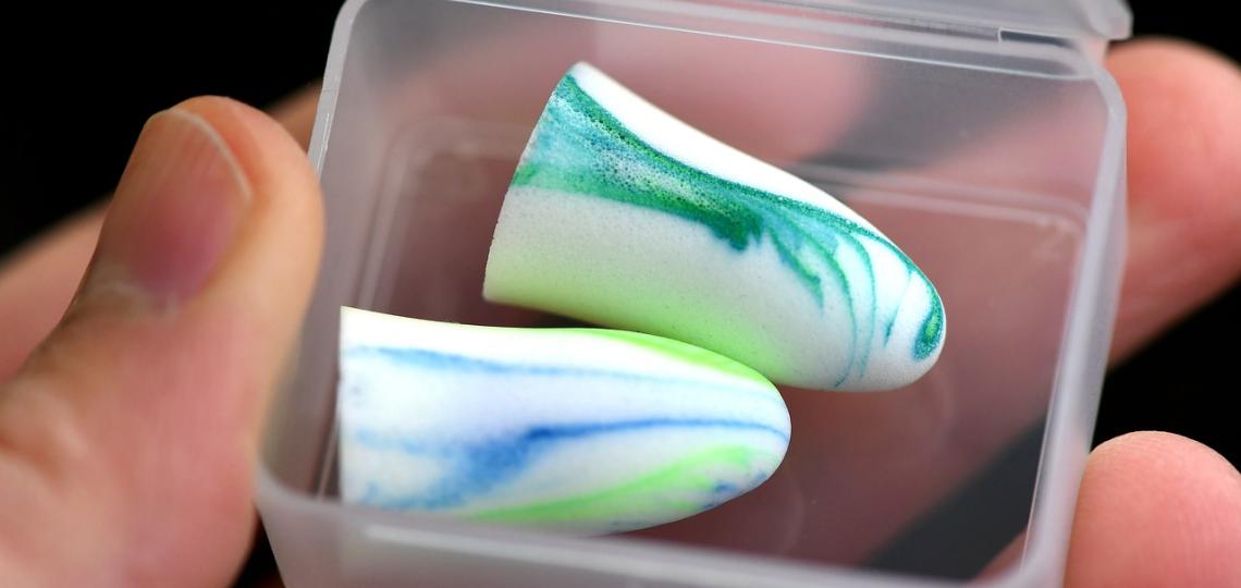 Close up photo of blue and white earplugs in a plastic box container. 