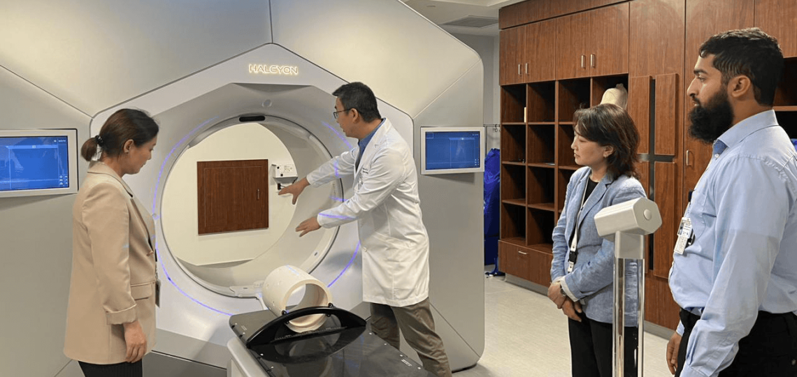Four doctors observing a radiation therapy bed device