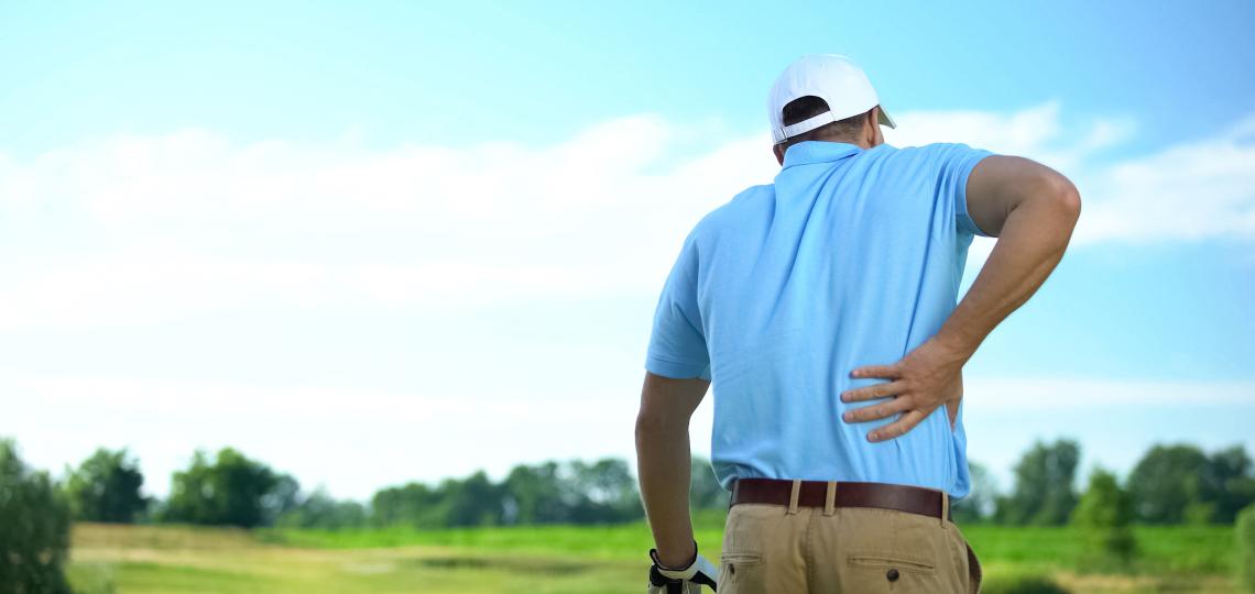 A man holding his back in pain.