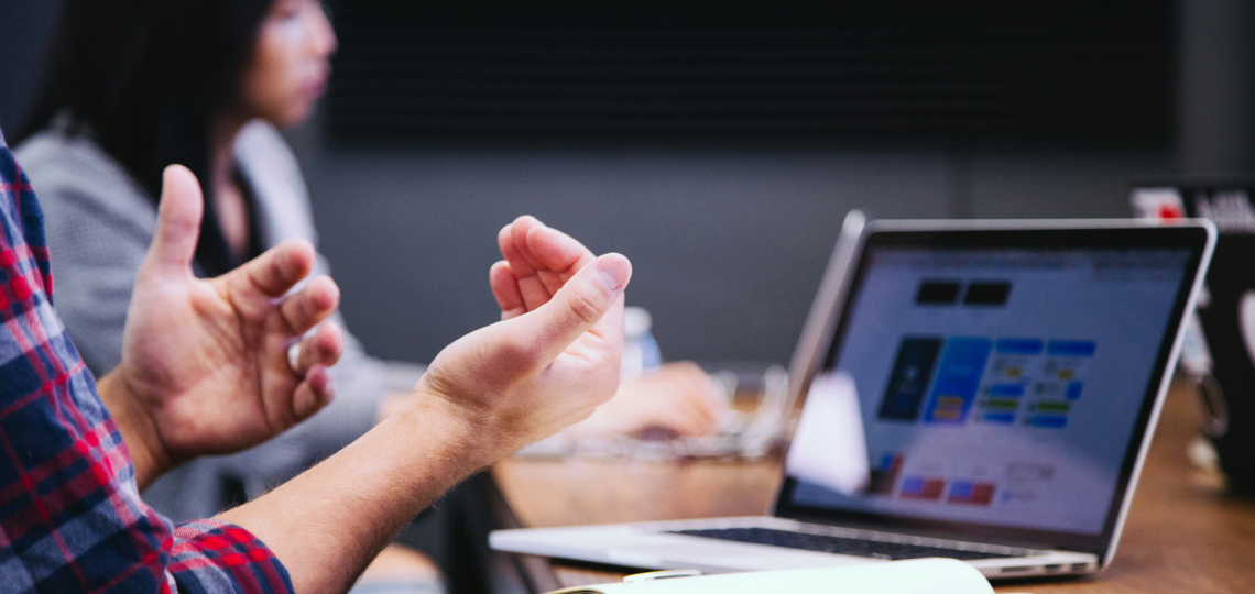 A person hands gesturing toward a laptop