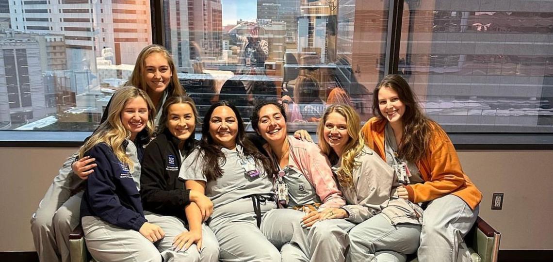 small group of women doctors sitting on a couch with the city skyline in the back smiling