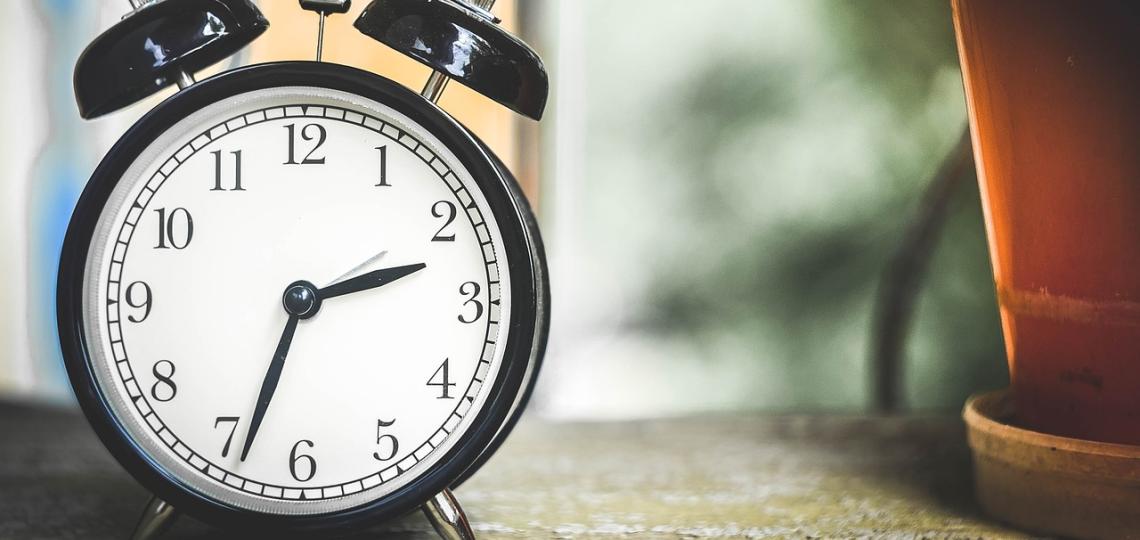 Photo of a round, black clock with alarm bells on top. 