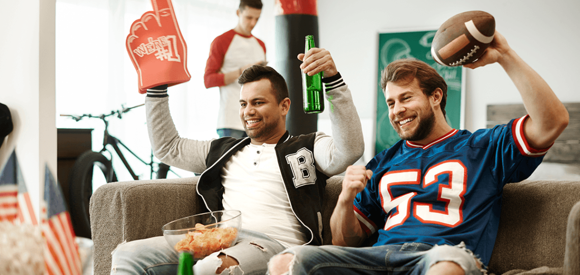 Football fans cheering in their living room. 