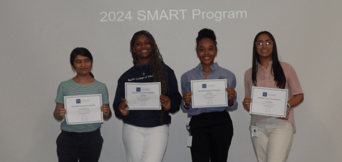 Four smiling students holding up certificates proudly. A sign behind them reads 2024 SMART Program.