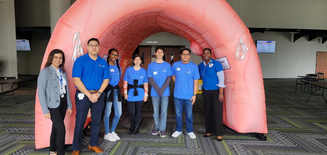 group of people smiling in front of a blow up arch