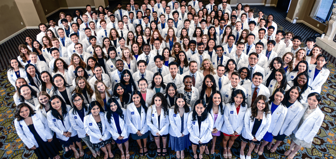 The entire class of 2023 wearing their white coats, as seen from a tall angle.
