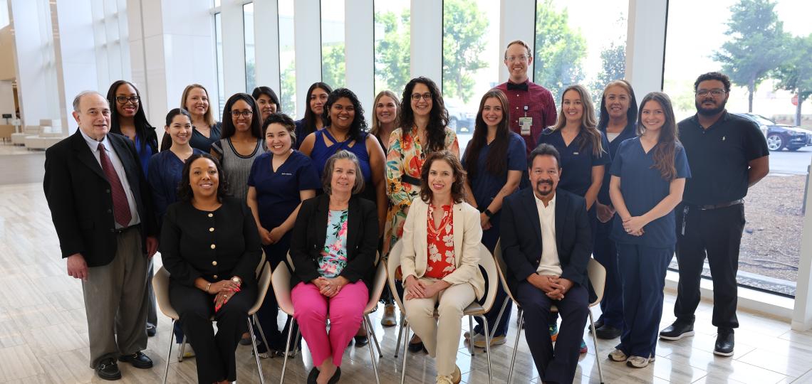 A group of 21 standing or sitting people smiling.