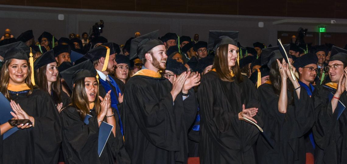 A photo of graduates clapping during their commencement ceremony. 