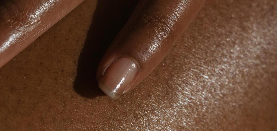 Close up photo of a hand touching their skin to represent skin health.