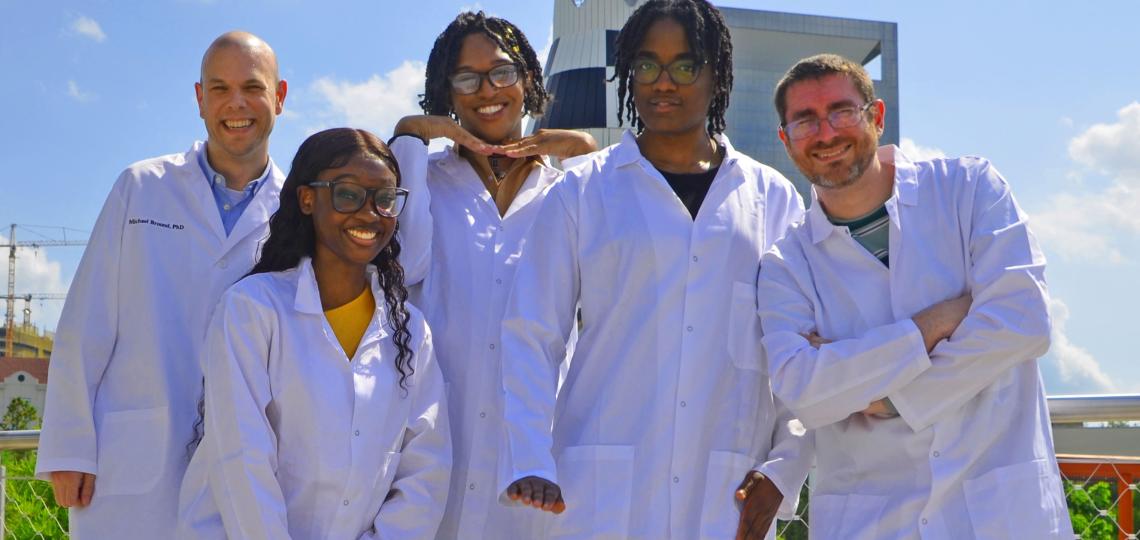 A group of 5 people in white coats outside.