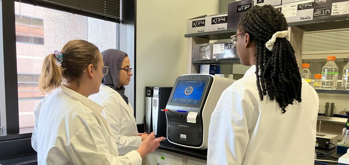3 people in a lab looking a medical equipment
