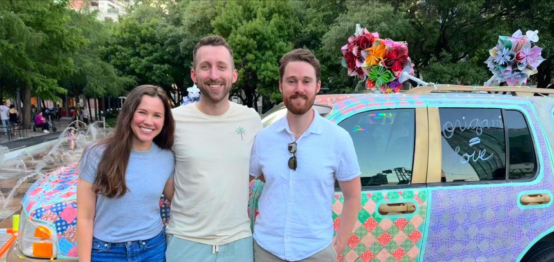 3 people standing in front of a colorful car, smiling