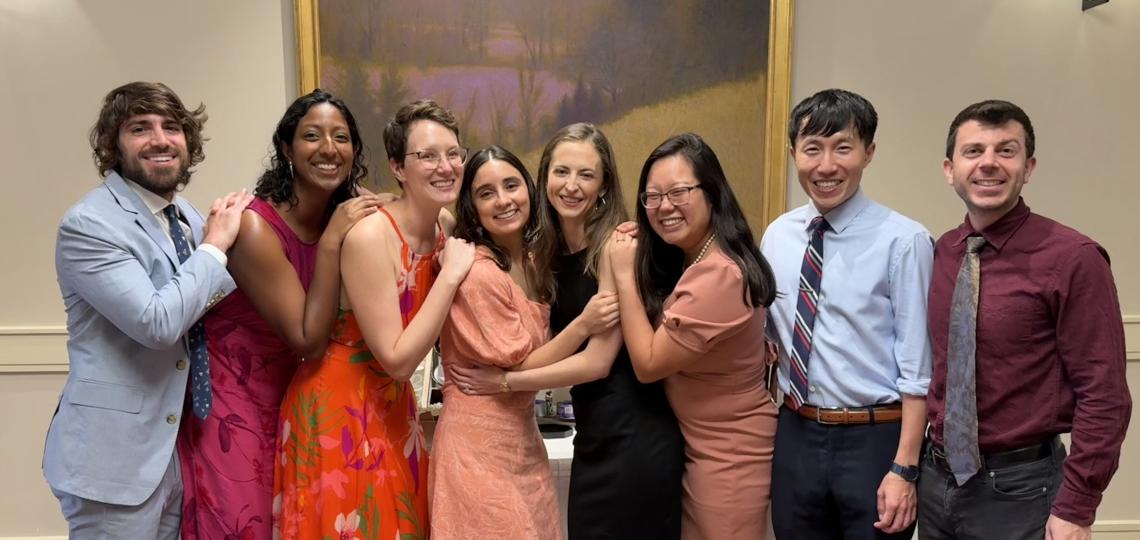 A group of smiling students posing in front of a painting