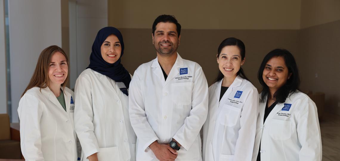 Five doctors in white coats smiling for the camera