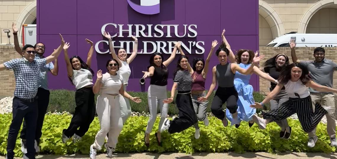 people jumping in front of Christus Childrens sign