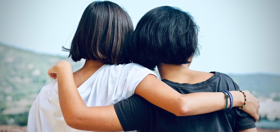 A photo taken from behind of two girls hugging, supporting each other during a difficult time. 