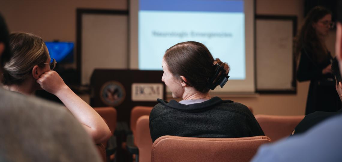 woman with her hair tied back sitting in a classroom