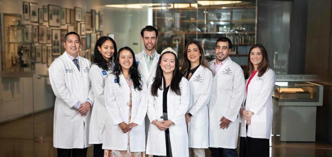 A group of smiling students wearing their white coats.