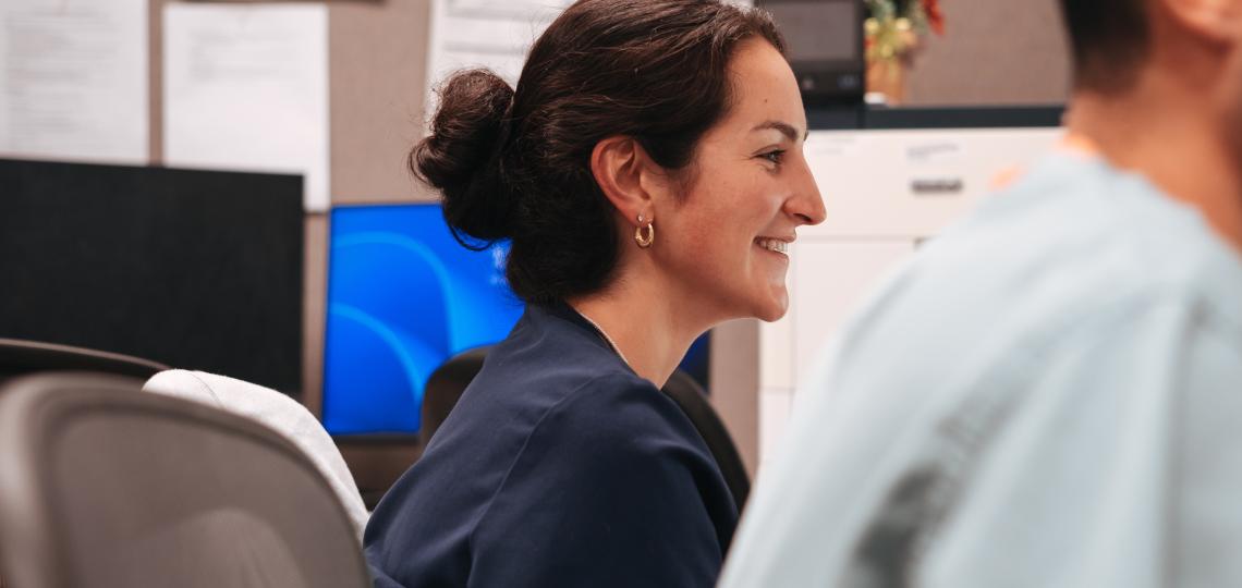 woman with her hair in a low bun sitting and smiling