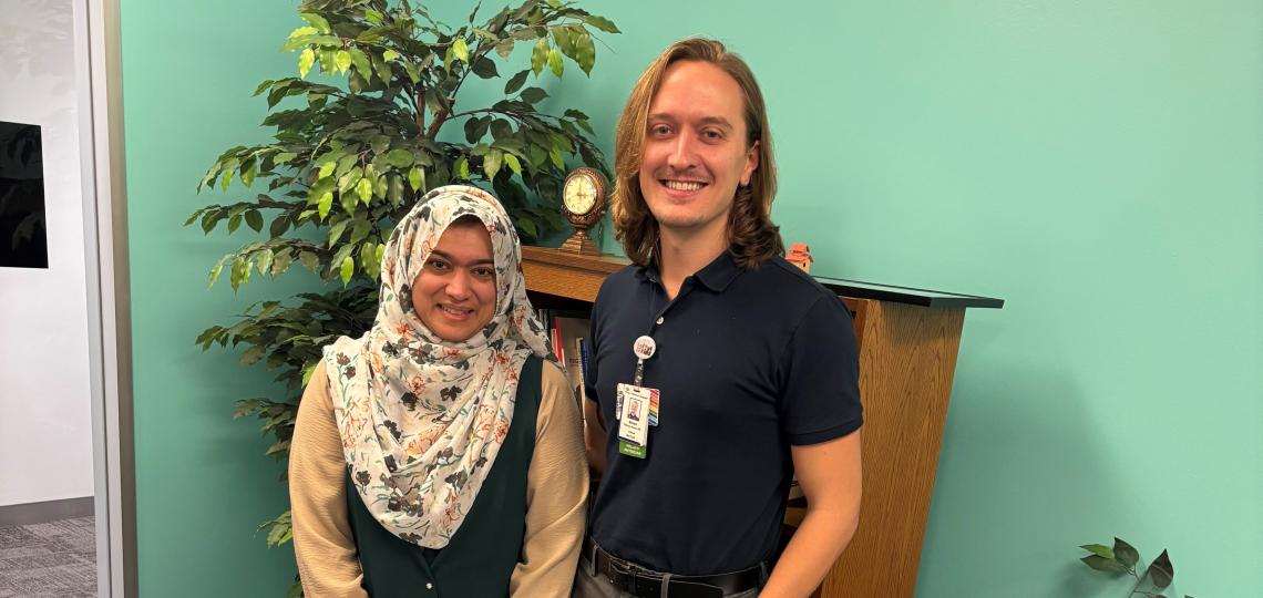 two people stnaind together in a room with teal walls, smiling