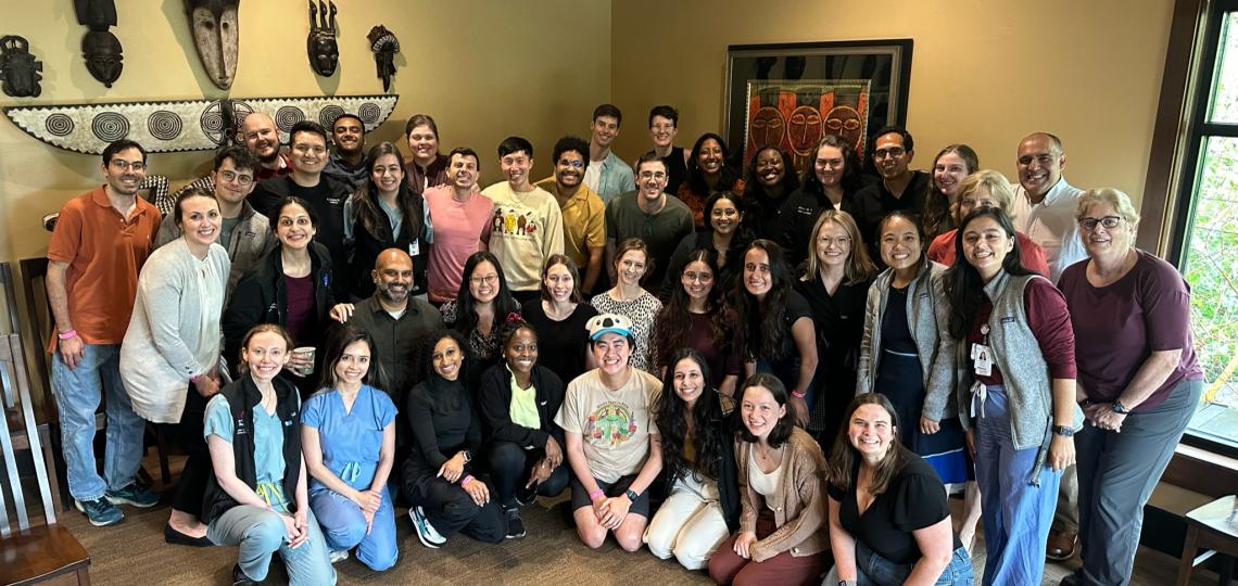 A large group of Medicine-Pediatrics residents in a large room decorated with masks