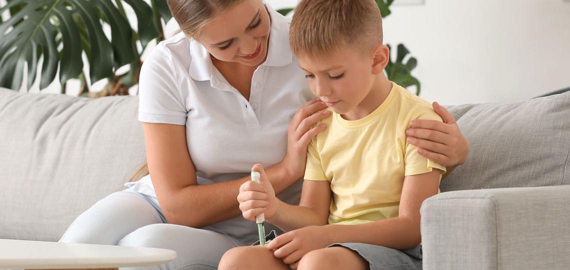 A parent helping their child inject themselves with an insulin shot. 
