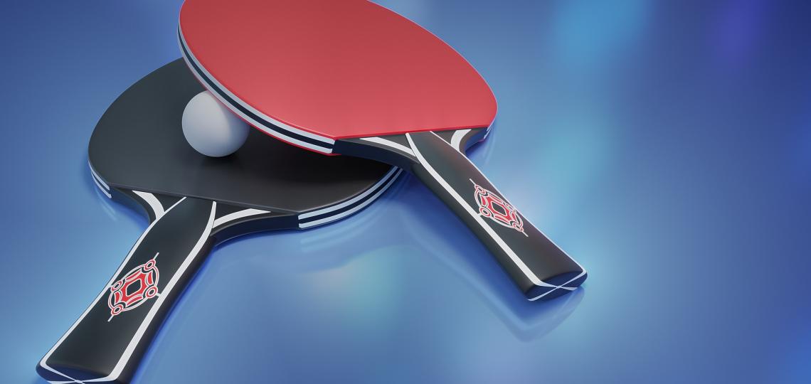 Photo of a ping pong paddle laying on top of a ping pong ball.