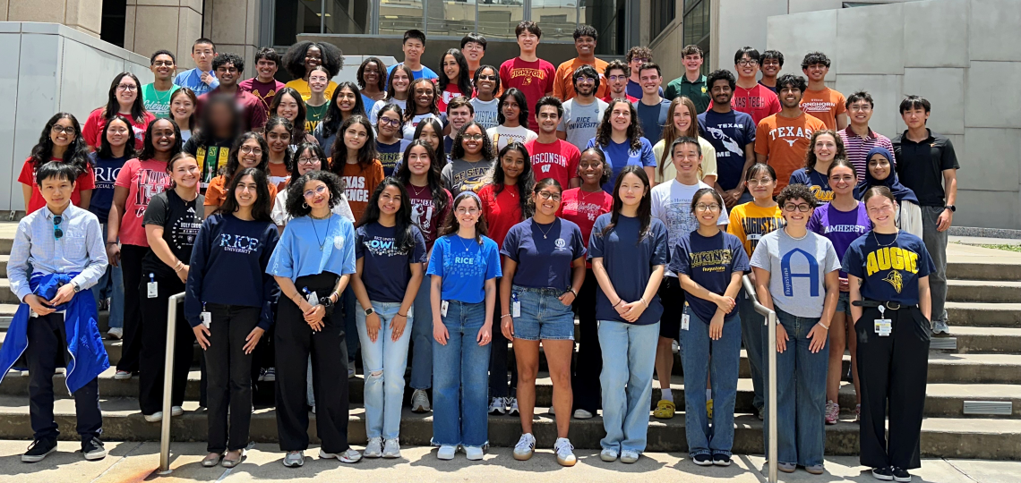 A large group of students wearing multi-colored shirts standing together on stairs for a group photo.