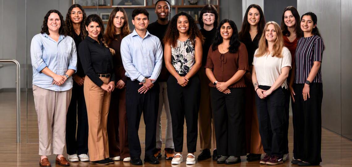 A group of students in nice clothing smiling and posing for the camera