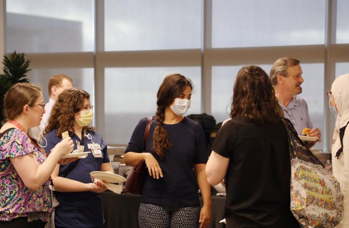 A group of presenters gather and mingle during the 2022 Annual Pathology and Immunology Trainee Research Symposium event.
